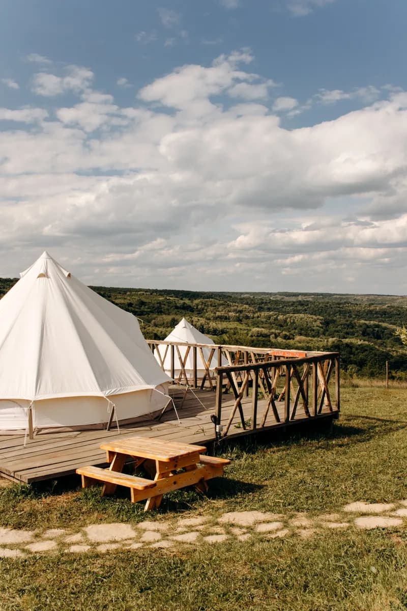 Imagen de ejemplo de BookNoFees: tiendas de glamping montadas sobre plataformas de madera en un paisaje abierto