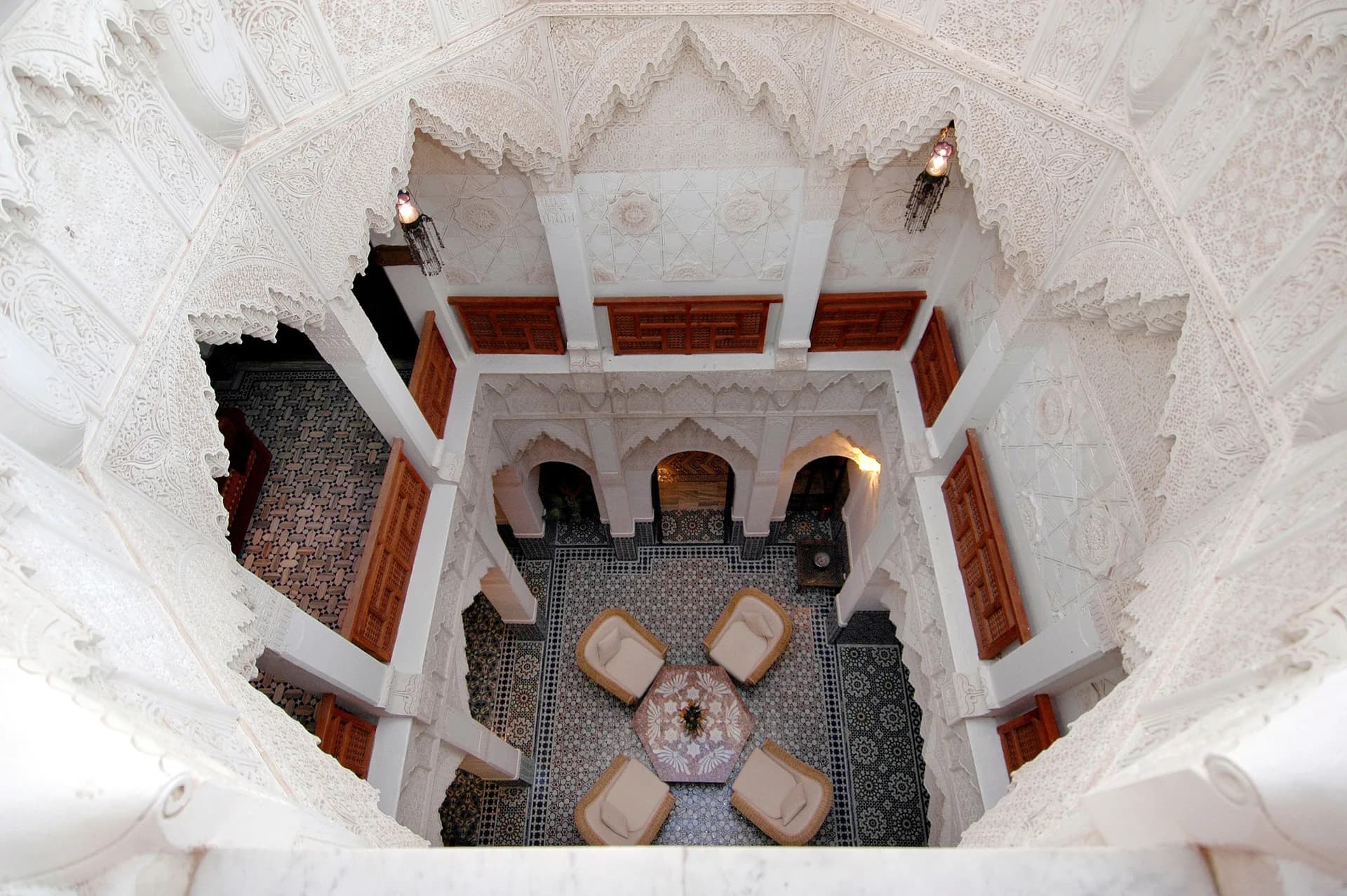 Imagen de ejemplo de BookNoFees: vista desde arriba de un patio interior de un riad con arcos decorados y asientos