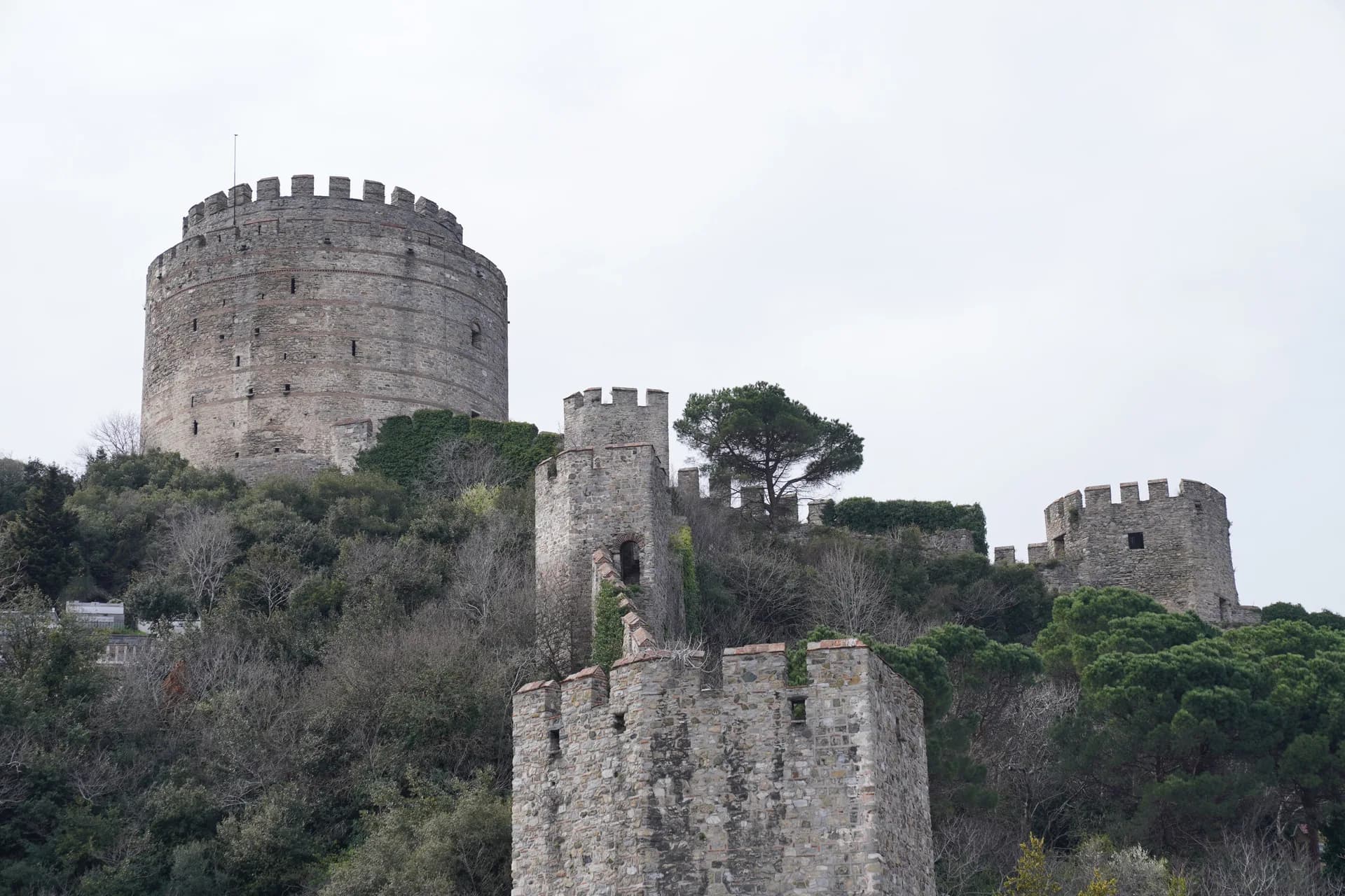 Imagen de ejemplo de BookNoFees: Torre redonda de piedra con murallas en una colina verde