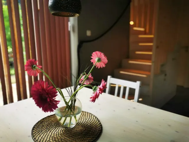 BookNoFees: alojamiento vacacional en Hieflau, Estiria, Austria – Sala de comer con una mesa blanca, un jarrón con flores rosas y una escalera de madera