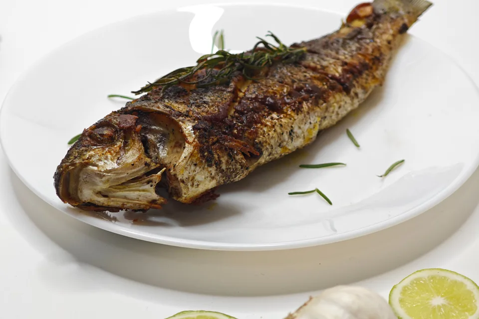 BookNoFees: Foto de ejemplo: Pescado entero a la parrilla en un plato blanco